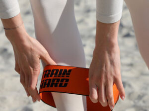 Close-up of hands placing custom printed resistance band on legs before exercise.
